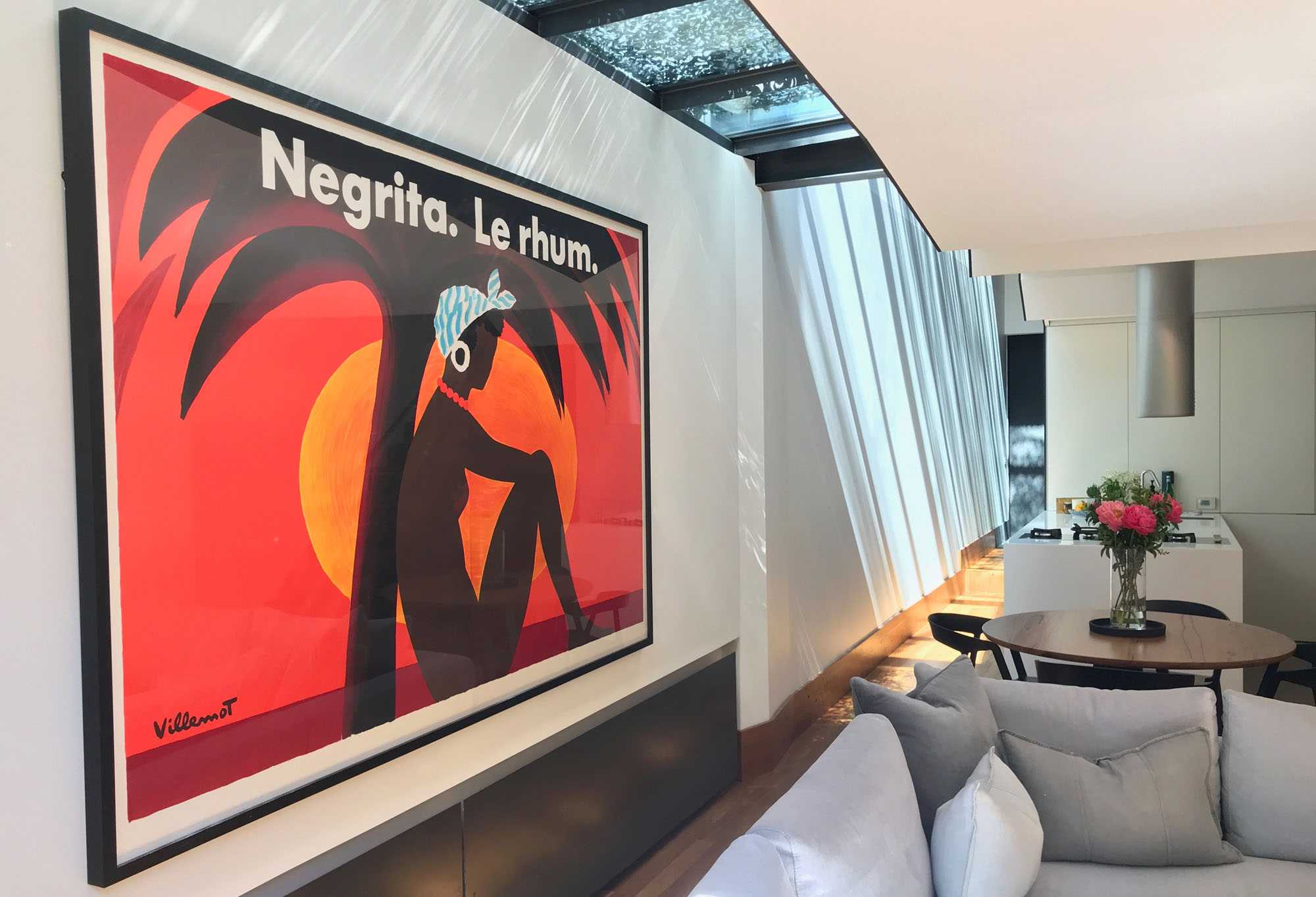 An abstract woman sits beneath palm tree with sunset behind in modern home; brown, red, orange