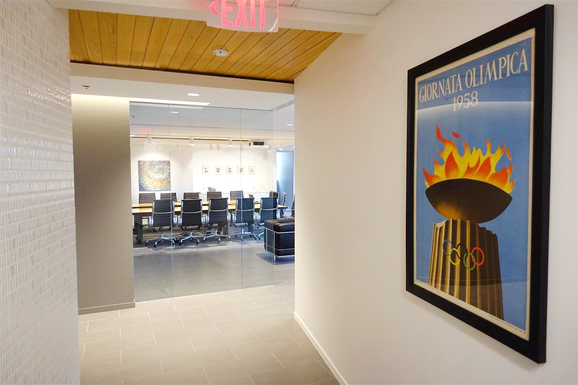 spacious office hallway with 1954 Olympic torch poster; black, white, brown, yellow, blue