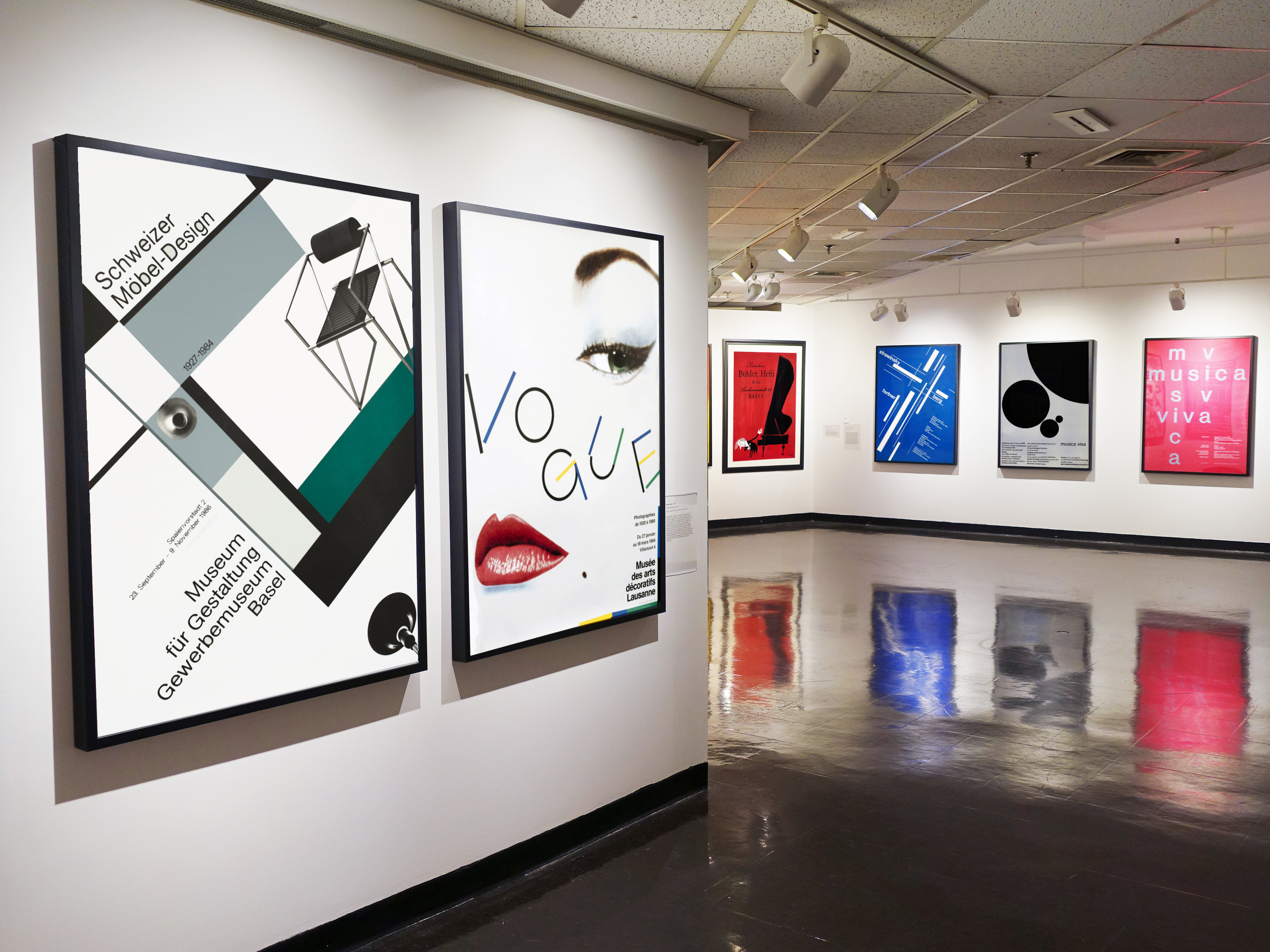 wide view of gallery with 6 posters on the walls; black, white, pink, blue, red